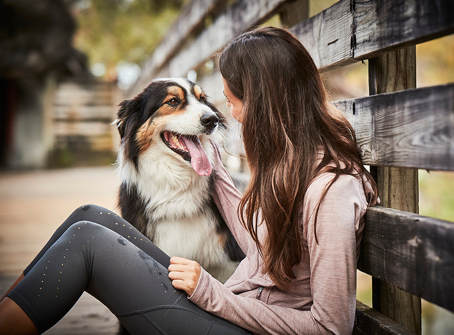 Woman and dog sitting by a fence