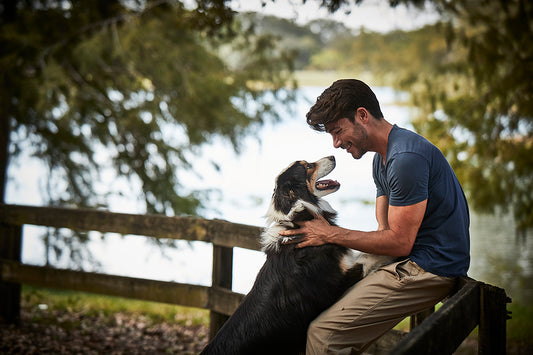 man and dog playing by a lake